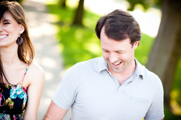 Obraz premium Young Couple Laughing and Walking on Sidewalk in Neighborhood