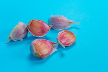 Five cloves of fresh garlic on a bright blue background. Spicy Healthy Vegetable Seasonings