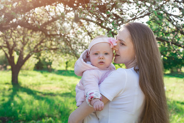 Beautiful young mother huggs little daughter. Walking with baby in the Park. Tenderness and care