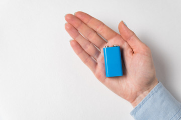 Blue PP3 battery lying on womens palm. Accumulator on white background
