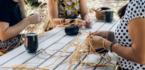 Females weaving baskets on the craft workshop. Hands holding the craftwork, close up shot.