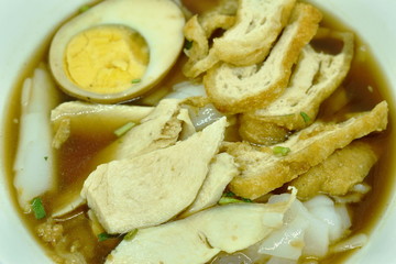 Chinese rice flour paste with slice chicken and fried tofu topping egg in brown soup