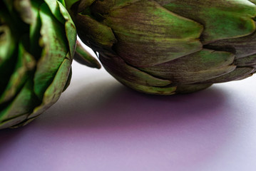 Fototapeta premium Artichokes close up on a purple surface.