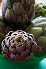 Artichokes close up on a green surface.