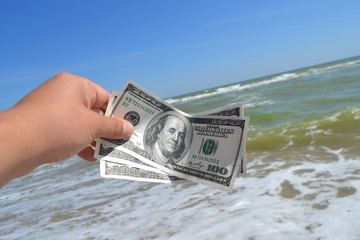 Girl holding a money bill of 300 dollars on background of sea waves