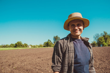 Happy male agro tourist in hat. Authentic rural farmer portrait. Agriculture worker. Vegetable garden. Rustic background. Country man. Manual labor. European farmland. Agrotourism concept. Copy space - obrazy, fototapety, plakaty