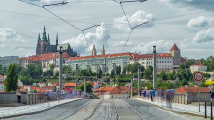 Red tram passing on Manes Bridge timelapse Manesuv Most and famous Prague Castle on the background in Prague, Czech Republic.