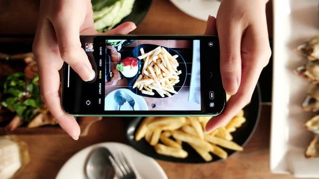 Woman hands taking a photo of food by smartphone.