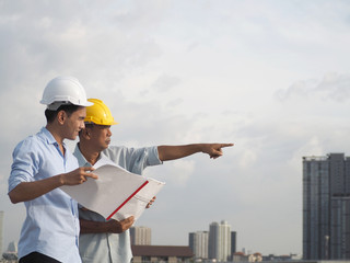 asian male engineer wear safety helmet or foreman and architects Asian people are pointing to new office.