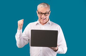 Happy mature man in specs holding pc