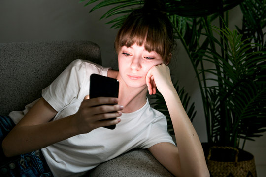 Teen Girl Holds Phone Sitting On Sofa Young Woman Looking At Cell Feeling Hopeless