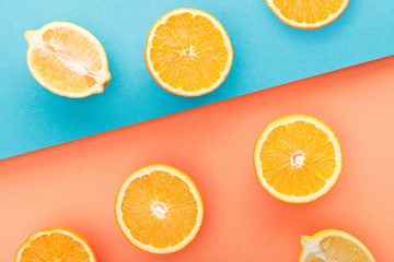 Fototapeta na wymiar Top view of cut oranges and lemon halves on blue and orange background