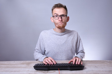 Funny nerd young businessman, man working on computer.Typing on the keyboard programmer in glasses in front of computer.