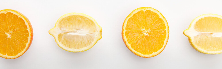 Top view of orange and lemon halves on white background, panoramic shot