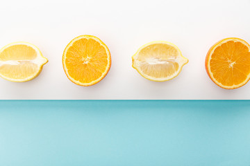 Top view of orange and lemon halves on blue and white background