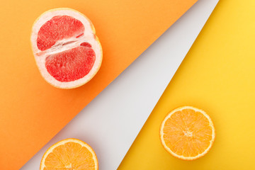 Fototapeta na wymiar Top view of citrus halves on yellow, orange and white background