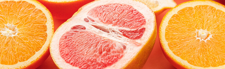 Citrus halves on orange background, panoramic shot