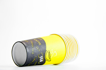A stack of disposable glasses. Coffee. Multi-colored paper. Close up on a white background