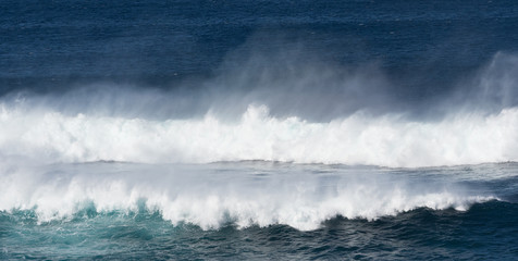 Obraz premium Dramatic white surf and spray as blue ocean waves roll