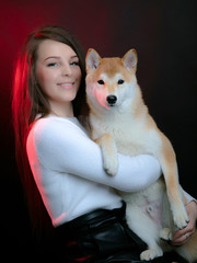 Girl with shiba inu. Beautiful girl holds a shiba inu dog in her arms. Studio photography, dark background.