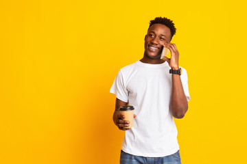 Portrait of handsome african guy standing with coffee to go