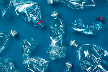 A lot of used plastic bottles on a blue background. The concept of pollution of the planet and the oceans with plastic waste.