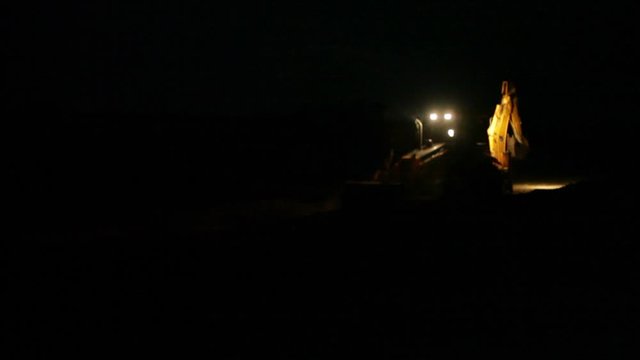 Bulldozer works at night around the clock, long shot