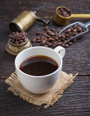 Hot coffee cup with premium arabica coffee beans on the wooden table.