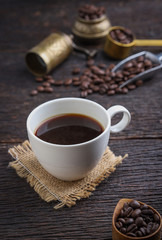 Hot coffee cup with premium arabica coffee beans on the wooden table.