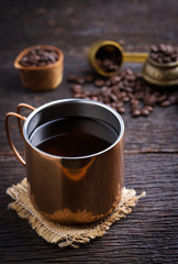 Hot coffee cup with premium arabica coffee beans on the wooden table.