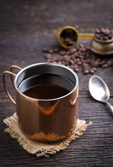 Hot coffee cup with premium arabica coffee beans on the wooden table.