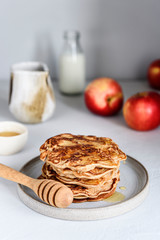 Homemade buckwheat apple pancakes with honey on light background. Pescajounes.  Hard light, deep shadow. Selective focus