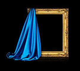 The wooden frame for the picture is covered with a silk blue cloth isolated on a black background. Antique golden frame.