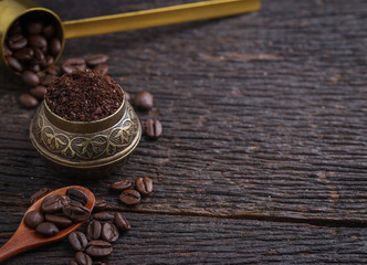Ground coffee and a vintage brass grinder on wooden table.copy space