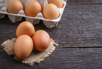 Raw eggs in egg box on rustic wooden background.
