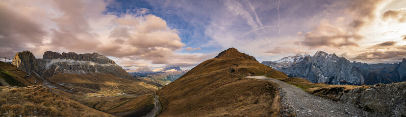 Autumn Dolomites mountain dramatic sunset scene from hiking path betwen Pordoi Pass and Fedaia Lake, Italy. Snowy Marmolada massif and Glacier in far right.