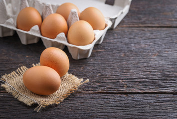 Raw eggs in egg box on rustic wooden background.