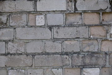 Old shabby, wrecked brick wall with grey cement mortar as background