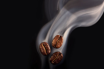 Roasted coffee beans. Seeds of freshly roasted coffee with smoke. Coffee beans closeup with...