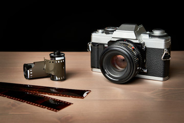 front view of a Classic analog 35 mm camera vintage and analog film rolls on wooden table