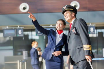 Young attractive stewardess pointing aircraft with the pilot in airport © MDBPIXS