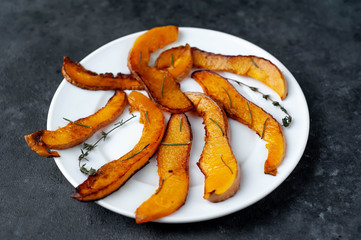 slices of fried pumpkin on a white plate on a stone background