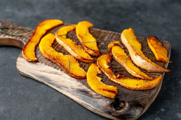 slices of fried pumpkin on a cutting board on a stone background