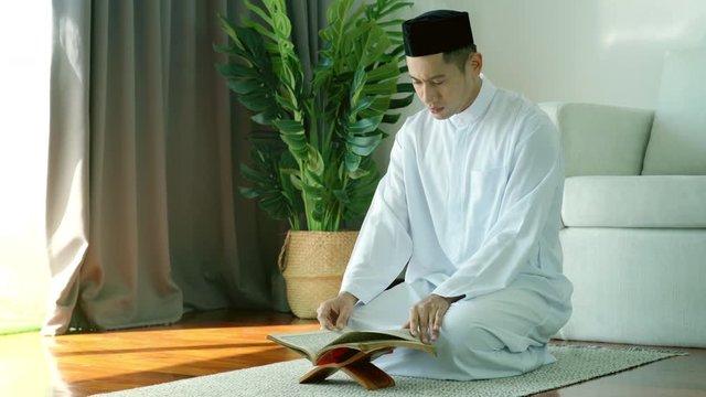 Portrait of Asian Muslim man reciting surah al-Fatiha passage of the Qur'an, in a daily prayer at home in a single act of sujud called a sajdah or prostration