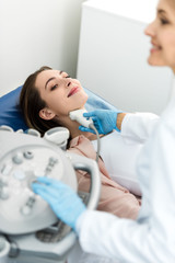 doctor examining thyroid of female patient with ultrasound scan in clinic