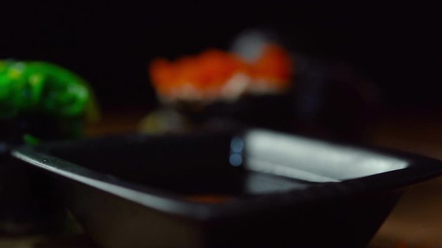 Close-up video of chopsticks being clamped with sushi dipped in sauce, a popular Japanese food.