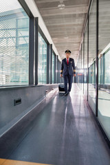 Portrait of mature pilot walking with his suitcase in airport