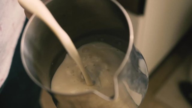 Barista holding a jug of foam texturing milk with the machine vaporizer, view from the top