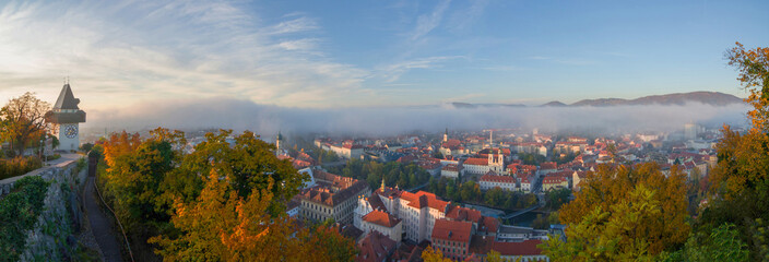 Cityscape of Graz and the famous clock tower (Grazer Uhrturm) on Shlossberg hill, Graz, Styria region, Austria, in autumn. Panoramic view.