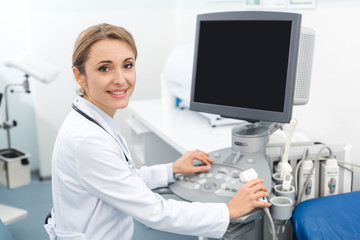 positive doctor working with ultrasound scanner with blank screen in clinic